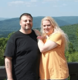 PAH patient, Rochelle, and her male caregiver, Tim, standing in front of green trees