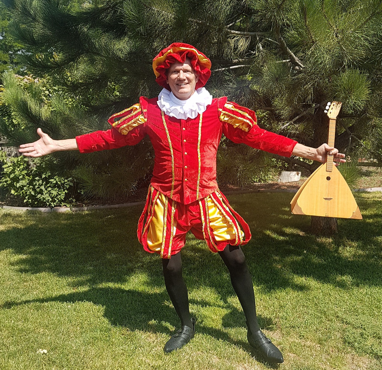 PAH patient, Steve, smiling in a red and gold theater costume outdoors holding a lute