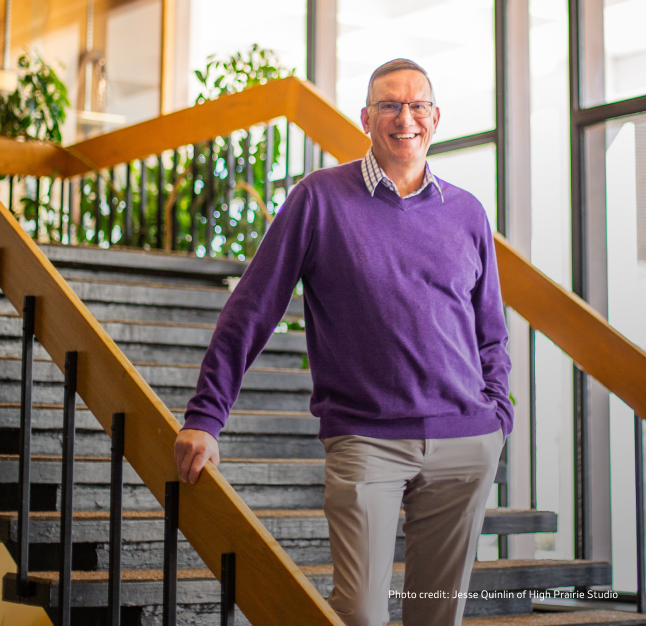 PAH patient, Steve, in a vibrant purple sweater smiling warmly on a staircase