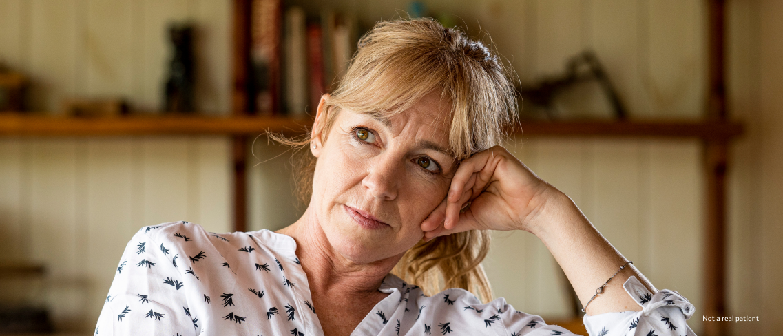 A woman in a black and white blouse gazing to her right with a calm expression and hand resting on her cheek