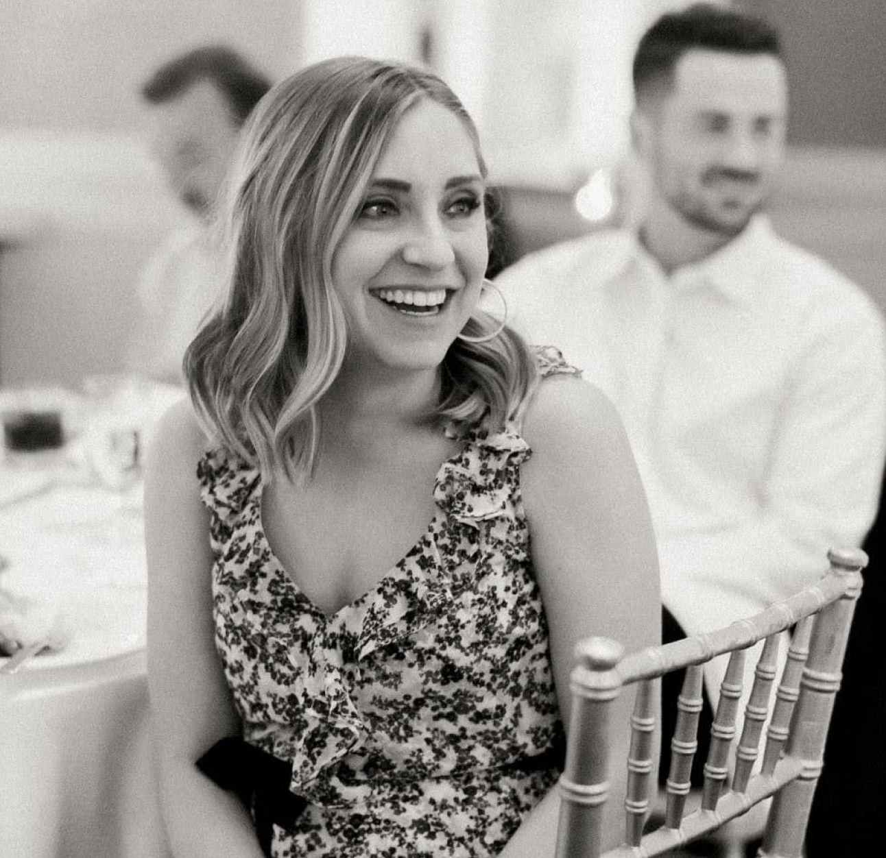 PAH patient, Chelsea, smiling while sitting on chair at a table looking to her left