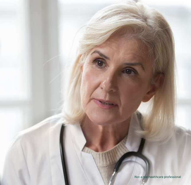 A female doctor wearing a white coat and stethoscope looking to her right with a calm expression