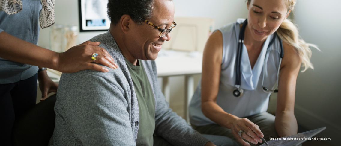 Female doctor pointing to a white board while talking with a male patient and his partner